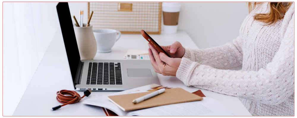Woman working at her desk in her home office, looking at her phone