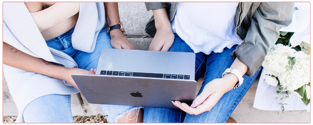  a coach and a client sitting on a bench focusing on a laptop together