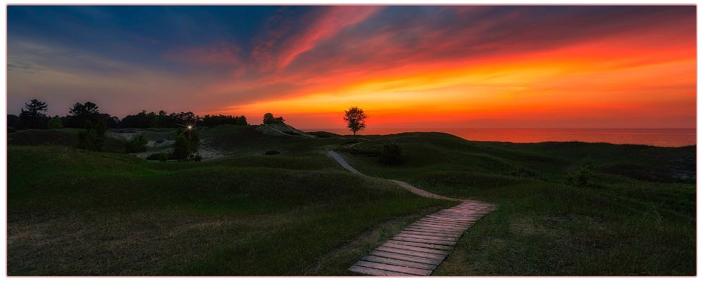 Sunset along a beach with a wooden path leading west.